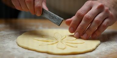 Baker scoring a loaf of bread